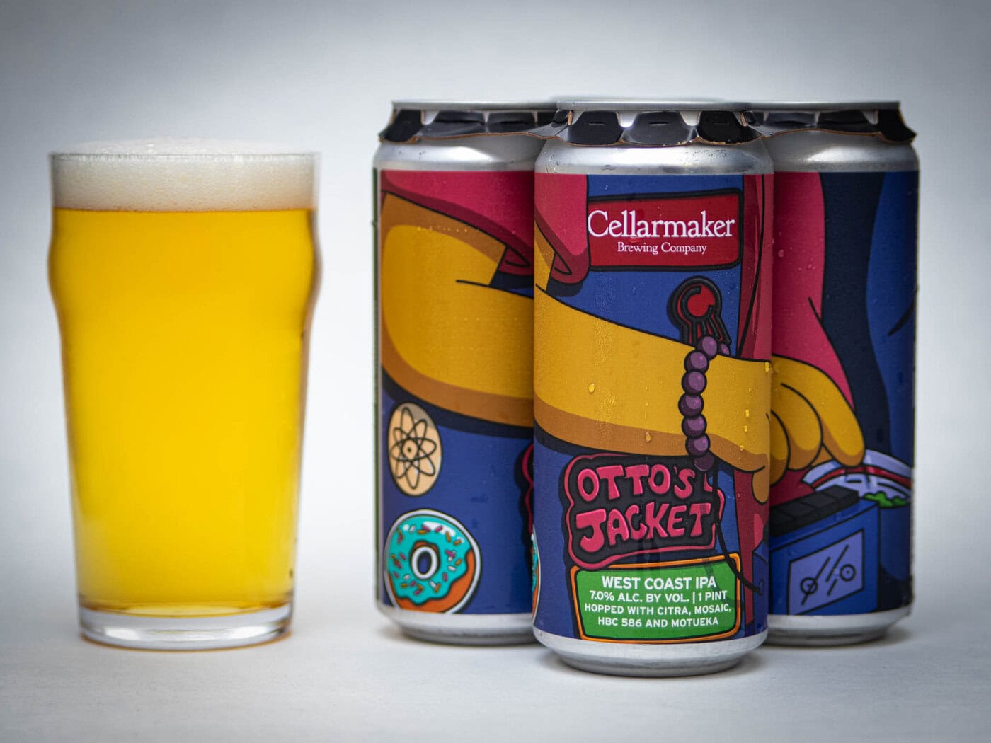 A Pint Glass Of Hazy Golden Beer Stands Next To Three Cans Of Cellarmaker Brewing Company’s Otto’s Jacket West Coast Ipa, Featuring Colorful, Cartoon-Style Artwork On The Labels.