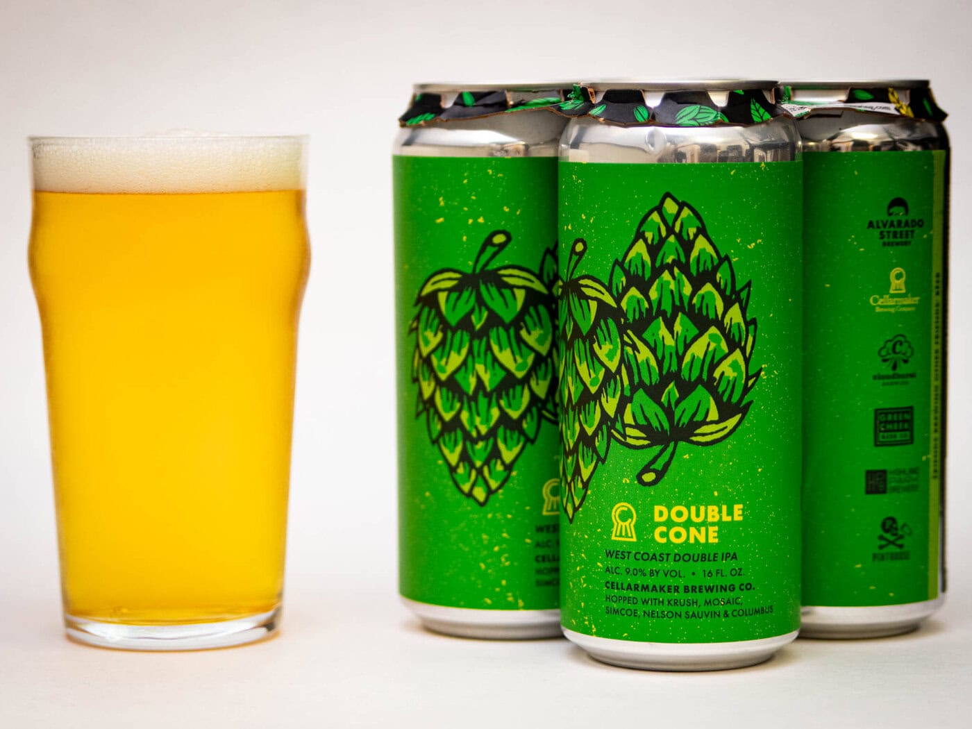 A Glass Of Pale, Hazy Beer Sits Beside Three Green Cans Labeled &Amp;Quot;Double Cone&Amp;Quot; With Hop Illustrations And Text Indicating It'S A West Coast Double Ipa From Alvarado Street Brewery.