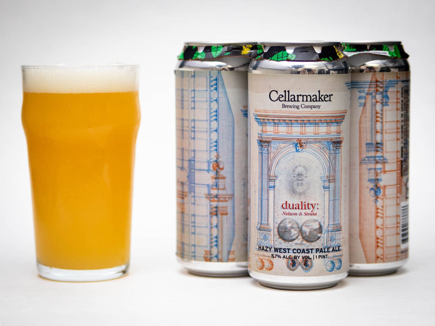 A Pint Glass Filled With Hazy, Golden Beer Stands Next To A Four-Pack Of Cellarmaker Brewing Company “Duality: Nelson &Amp;Amp; Strata” West Coast Pale Ale Cans With Intricate Architectural Designs On The Labels.