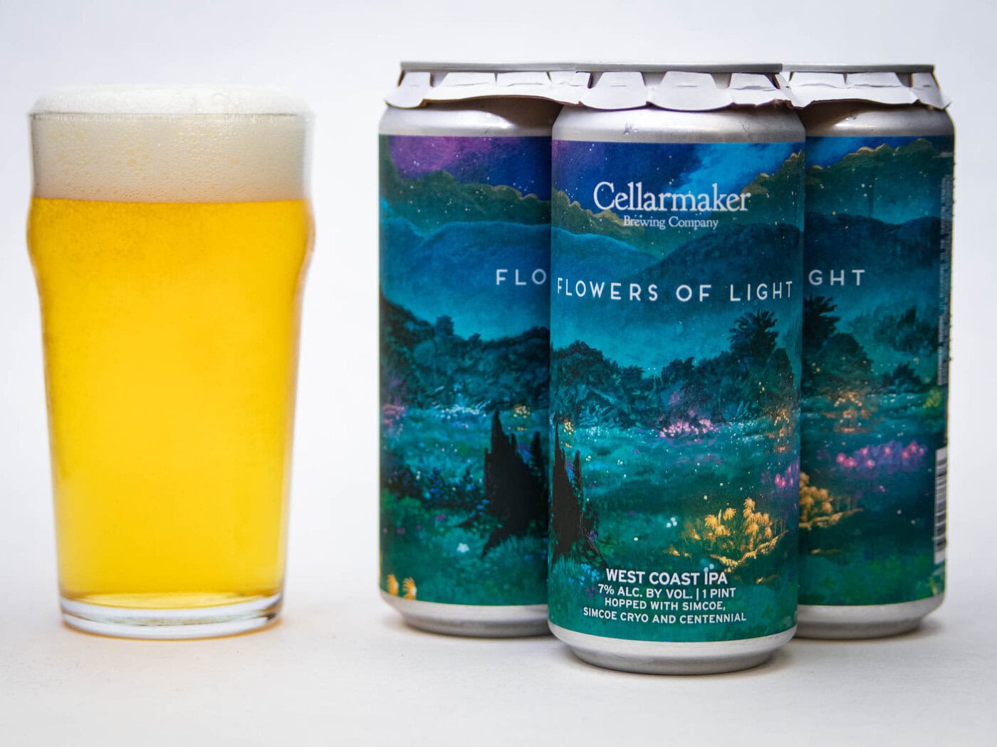 A Pint Glass Of Hazy Golden Beer Sits Next To Four Cans Of Cellarmaker Brewing Company'S &Amp;Quot;Flowers Of Light&Amp;Quot; West Coast Ipa, Featuring A Colorful, Scenic Landscape Label.