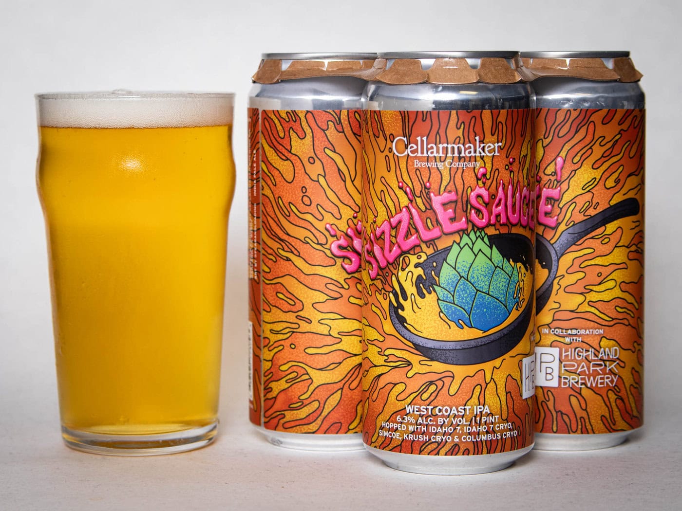 A Pint Glass Of Hazy Yellow Beer Sits Beside A Four-Pack Of Colorful Cans Labeled &Amp;Quot;Foreign Object - Wc Ipa - Tdne Collab,&Amp;Quot; Featuring Vibrant Orange Artwork With A Hop In A Sizzling Pan.