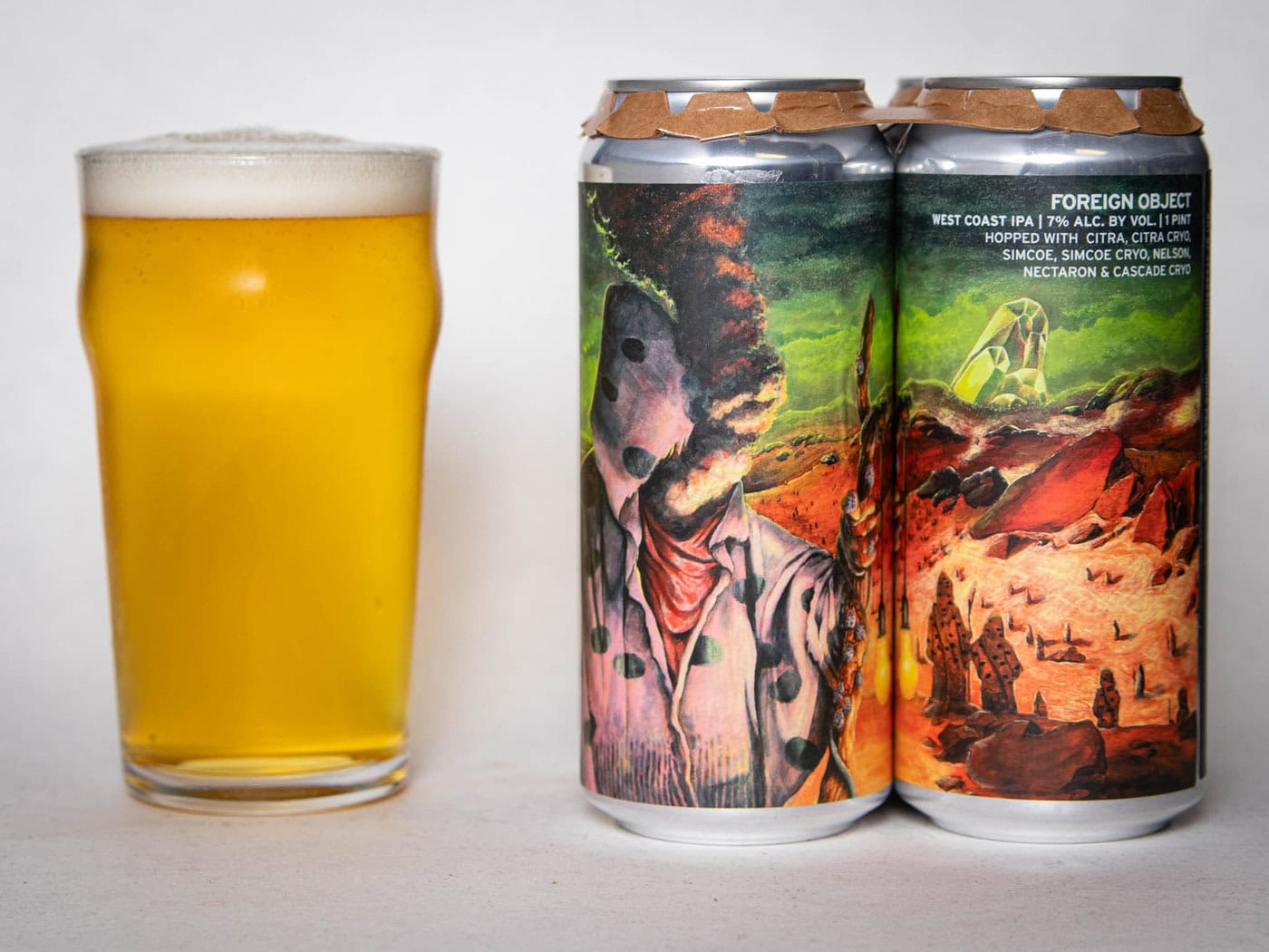 A Pint Glass Of Hazy Golden Beer Sits Beside Two Colorful Cans With Surreal, Sci-Fi Artwork Labeled &Amp;Quot;Foreign Object - Wc Ipa - Tdne Collab.